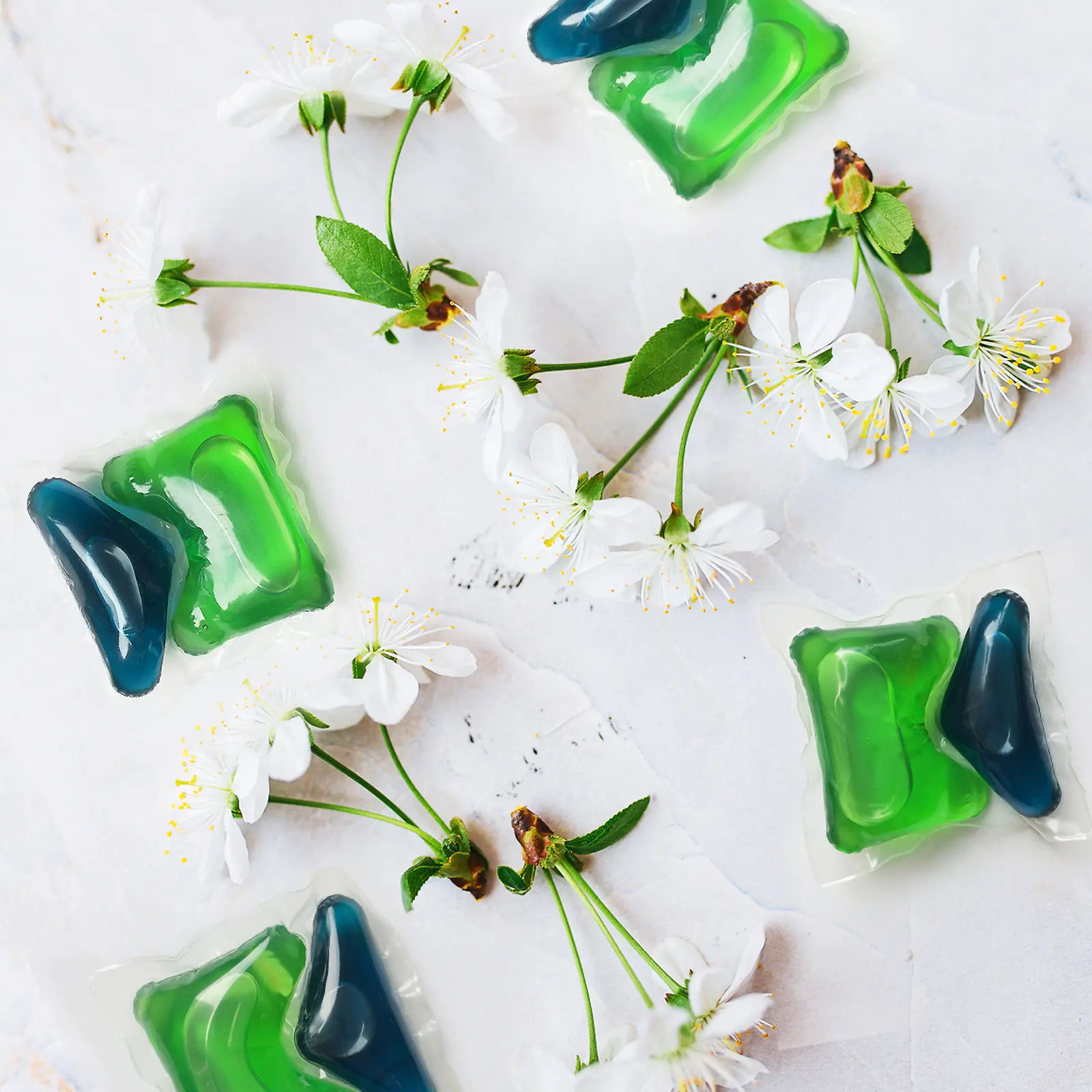 Two green and blue Henkel Persil tabs with cherry blossoms around 