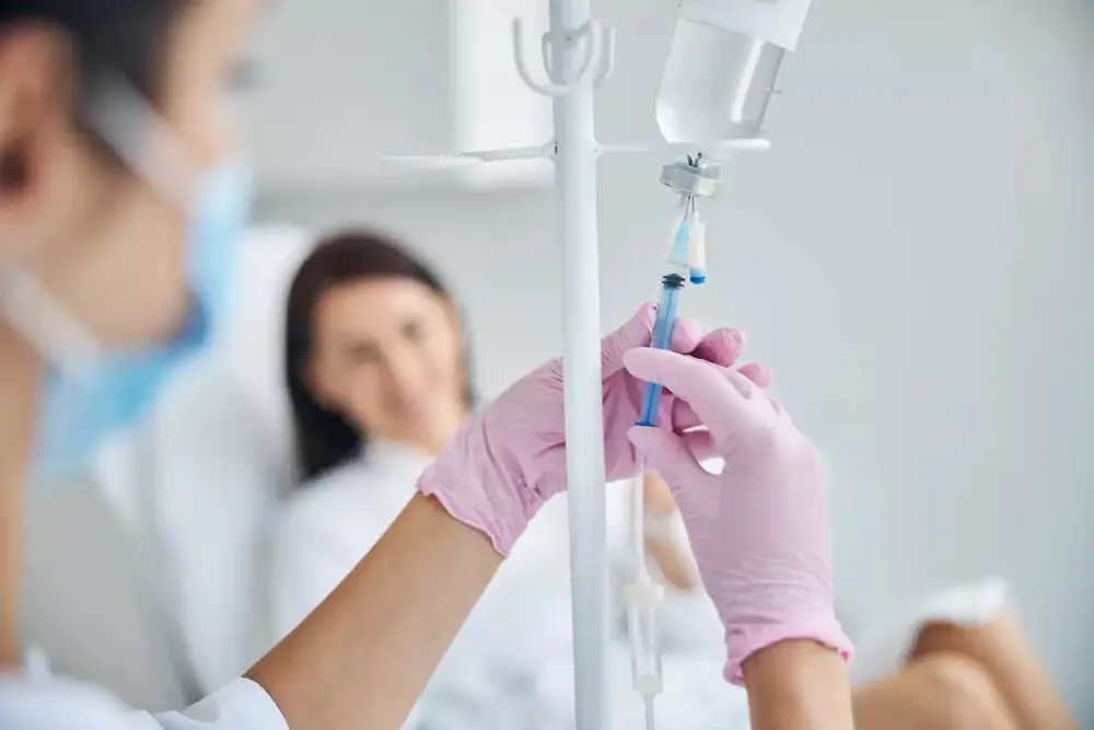  Medical professional holding an IV drip bag in a healthcare setting.