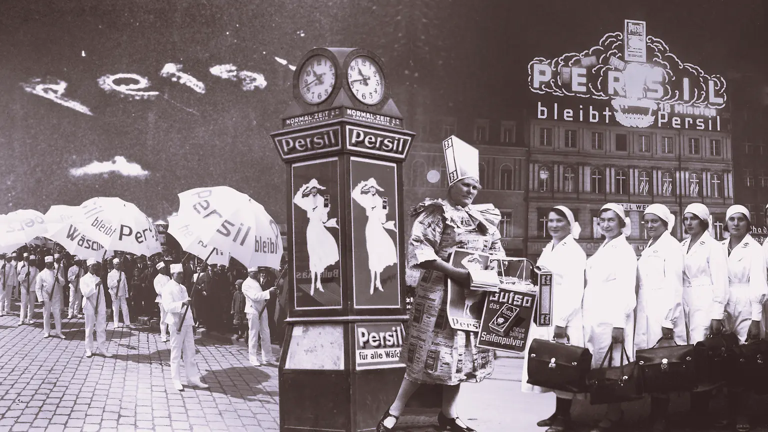Vintage Persil advertisement collage featuring people holding branded umbrellas, a decorative clock with posters, and a building with illuminated Persil signage in the background.