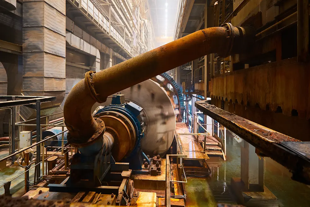 Photograph of an industrial facility featuring a pipe connected to a cylindrical machine.